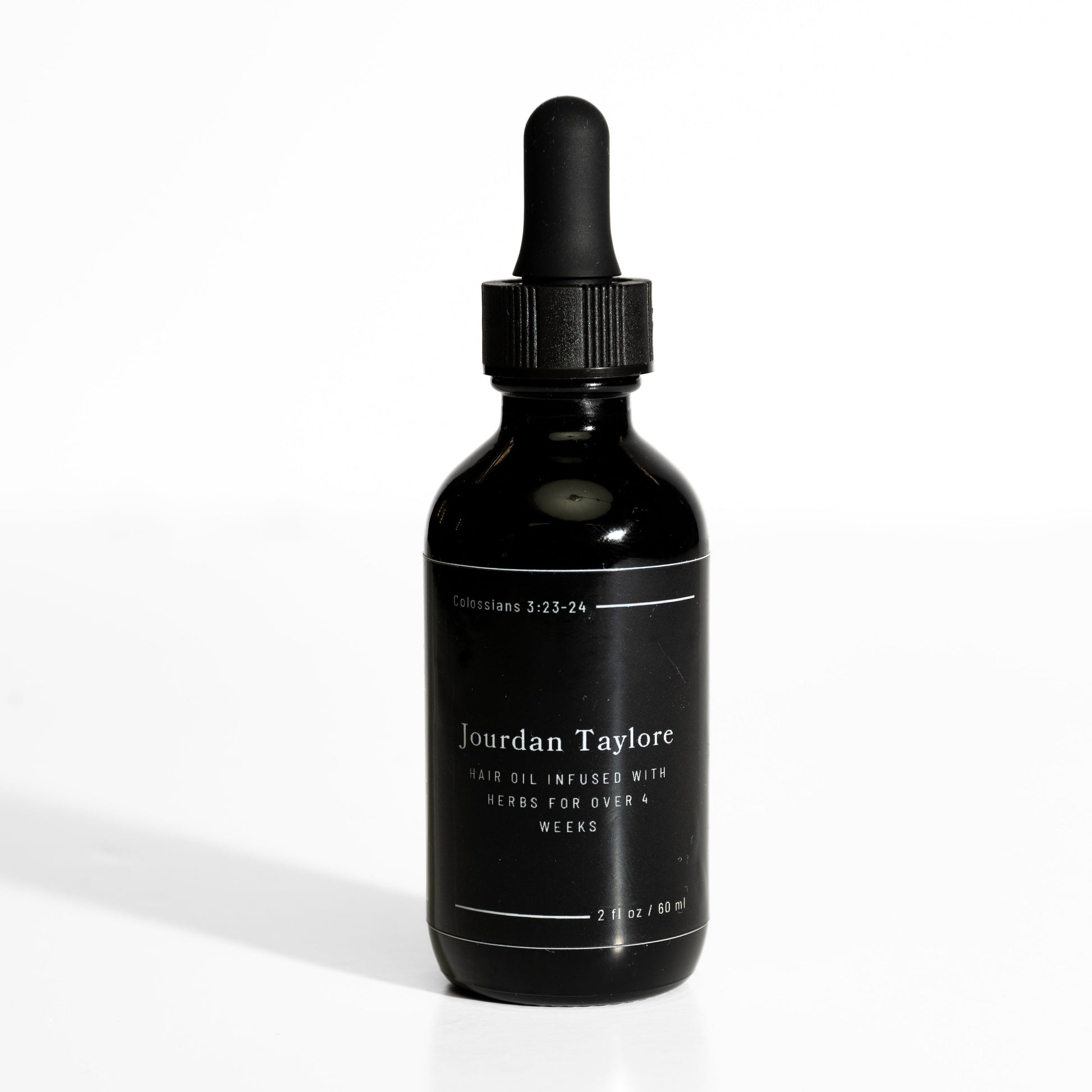 A black bottle with a dropper filled with a golden-brown hair oil, labeled as 'Medicinal Hair Elixir' by Jourdan Taylore.