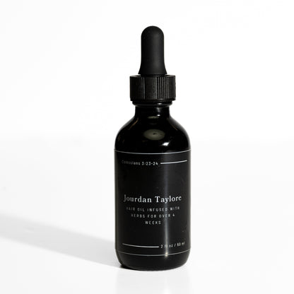 A black bottle with a dropper filled with a golden-brown hair oil, labeled as 'Medicinal Hair Elixir' by Jourdan Taylore.